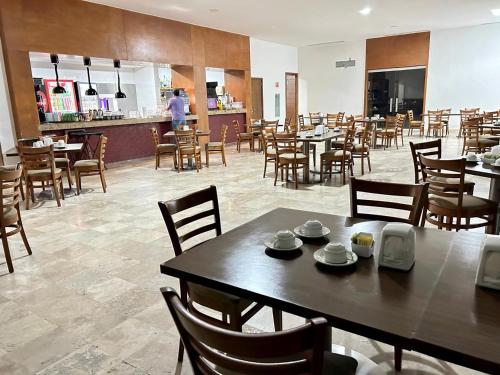 a restaurant with tables and chairs and a person in the kitchen at Departamento Mayan Lakes T9 - Albercas, club de playa, tenis, pádel y más in Acapulco