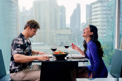 a man and a woman sitting at a table with wine glasses at Golden Tulip Mandison Suites in Bangkok