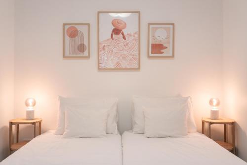 a bedroom with two white beds with two lamps at Barlavento by An Island Apart in Porto Santo