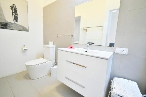 a white bathroom with a toilet and a sink at Villa Philibert in Riambel