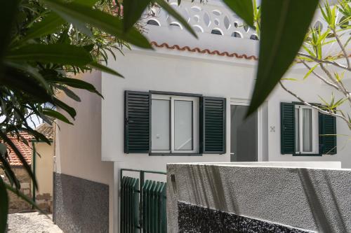 a white house with green shutters and a fence at Barlavento by An Island Apart in Porto Santo