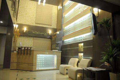 a lobby with a waiting area with white chairs and a tv at Hotel Apple Inn Vapi in Vapi