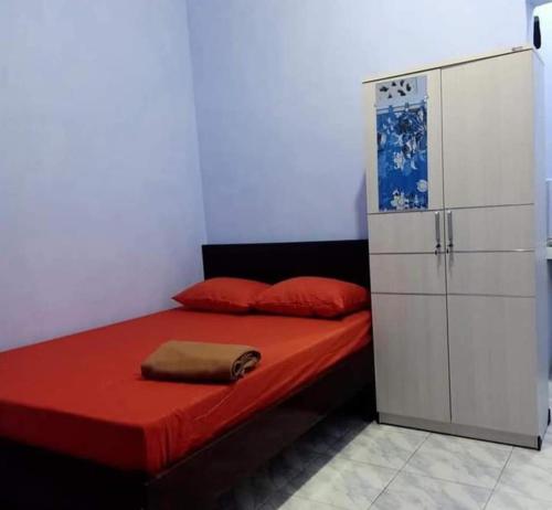 Un dormitorio con una cama roja y un armario blanco. en Penginapan Herlandy, en Komodo Labuan Bajo Airport