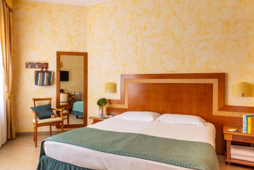 a bedroom with a large bed and a chair at Hotel & Residence Venezia 2000 in Venice-Lido