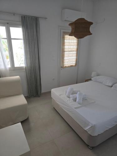 a white bedroom with a bed and a chair at Oasis in Kamarai