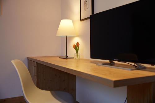 a desk with a television and a lamp on it at Hotel Luitpold am See in Prien am Chiemsee