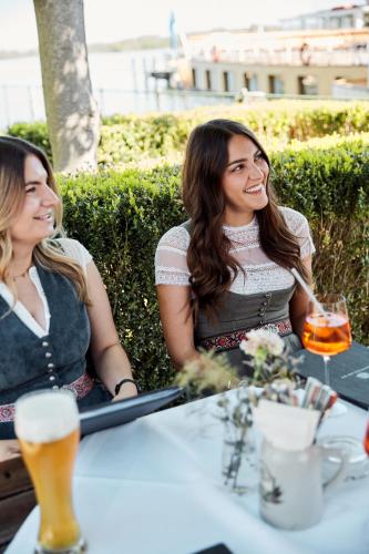 two women sitting at a table with a glass of beer at Hotel Luitpold am See in Prien am Chiemsee