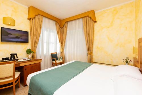 a bedroom with a bed and a desk with a computer at Hotel & Residence Venezia 2000 in Venice-Lido