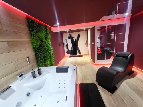 La salle de bains est pourvue d'une baignoire et d'une chaise noire. dans l'établissement L'incontournable Love Room, à Peyrins