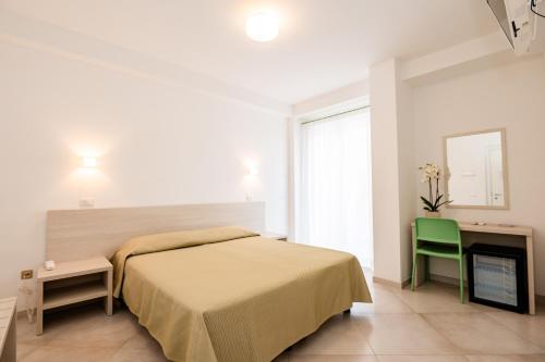 a bedroom with a bed and a green chair at Hotel Sfinalicchio in Vieste