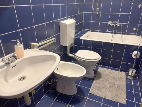 a blue tiled bathroom with a toilet and a sink at Apartments Radulović in Biograd na Moru