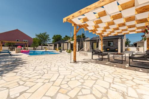 a patio with a wooden pergola and a pool at Unique Villa V with large pool in Benkovac