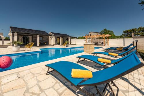 a row of blue lounge chairs next to a swimming pool at Unique Villa V with large pool in Benkovac