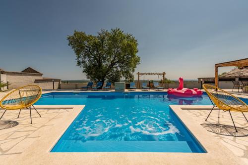 a swimming pool with two chairs and a red raft at Unique Villa V with large pool in Benkovac