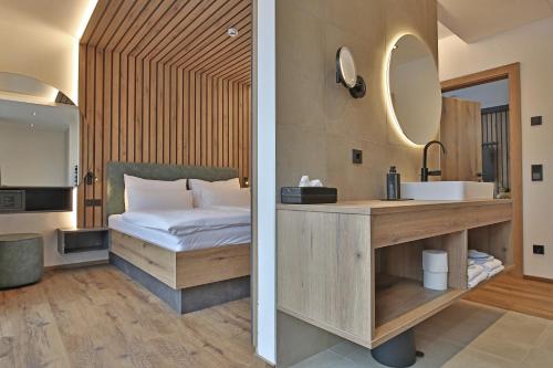 a bathroom with a bed and a sink and a mirror at Das Goldjuwel - Luxury Apartments with private Spa in Goldegg