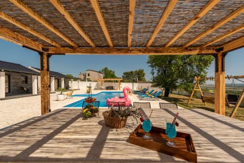 a patio with a wooden pergola and a swimming pool at Unique Villa V with large pool in Benkovac