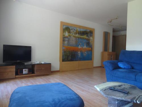 a living room with a blue couch and a tv at Artist Apartments & Hotel Garni in Zermatt