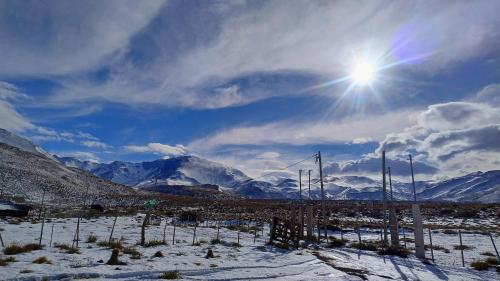 a view of a snowy mountain range with the sun at La Horqueta in Malargüe