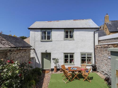 a white house with a table and chairs in the yard at Cleve Cottage in Lyme Regis
