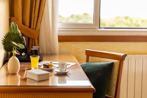 a table with a drink and a plate of food on it at Hotel & Residence Venezia 2000 in Venice-Lido