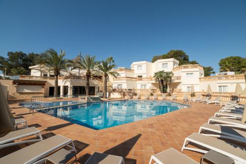 a large swimming pool with chairs and palm trees at Apartamentos Azul Playa in Cala d´Or