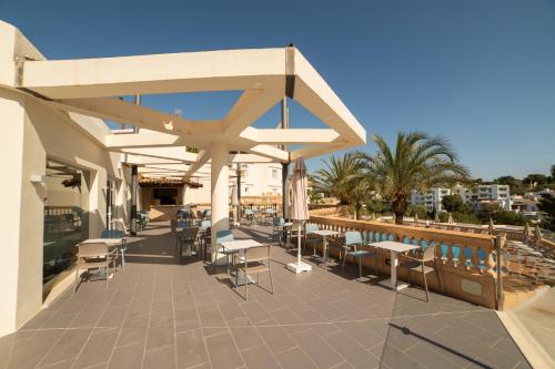 a patio with tables and chairs on a building at Apartamentos Azul Playa in Cala d´Or
