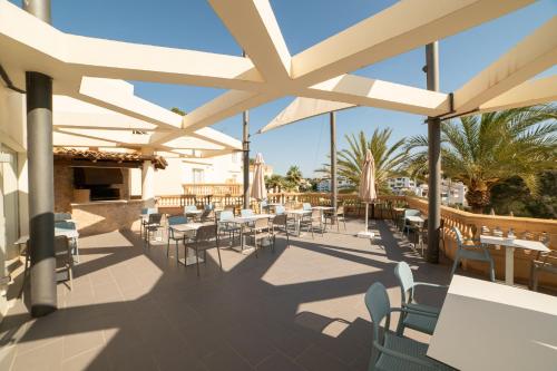 a patio with tables and chairs and umbrellas at Apartamentos Azul Playa in Cala d´Or