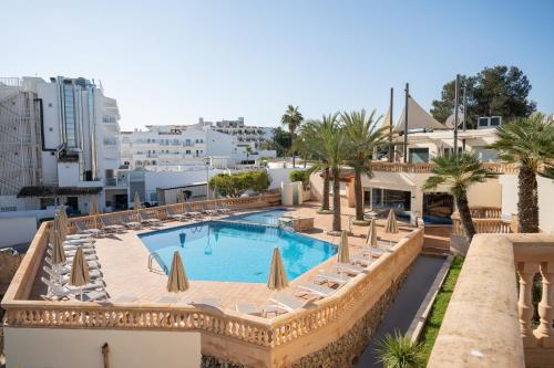 a view of a swimming pool with chaises and palm trees at Apartamentos Azul Playa in Cala d´Or