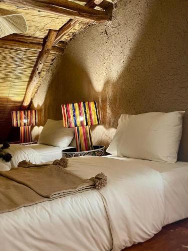 two white beds in a room with a wall at Hotel & Spa La Ferme El Dar in Marrakech
