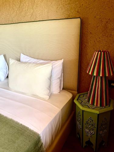 a bedroom with a bed and a nightstand with a lamp at Hotel & Spa La Ferme El Dar in Marrakech