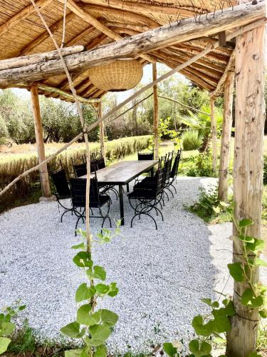 a table and chairs under a wooden pergola at Hotel & Spa La Ferme El Dar in Marrakech