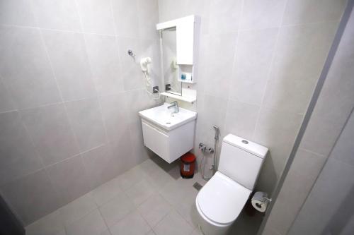 a white bathroom with a toilet and a sink at Passage Hotel in Baku