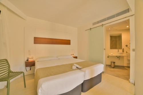 a bedroom with a large bed and a chair at Apartamentos Azul Playa in Cala d´Or
