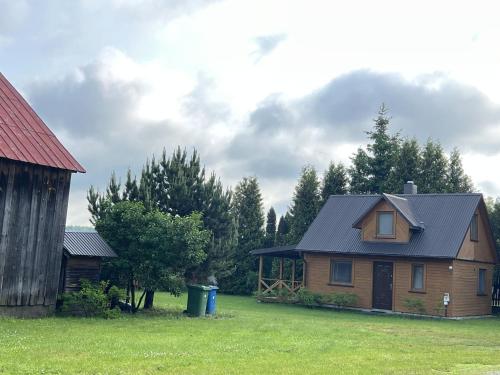 a wooden house with a black roof in a field at Agroturystyka Katarzyna Tarasiewicz in Stary Folwark