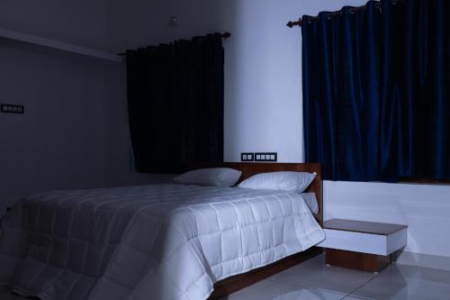 a bedroom with a white bed and a window at Salora by Mohanam Comfort Homes in Kazhakuttam