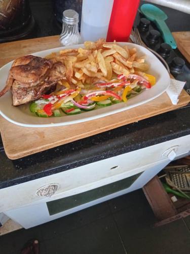 a plate of food on a cutting board with french fries at Riverstone Guest Lodge in Harare