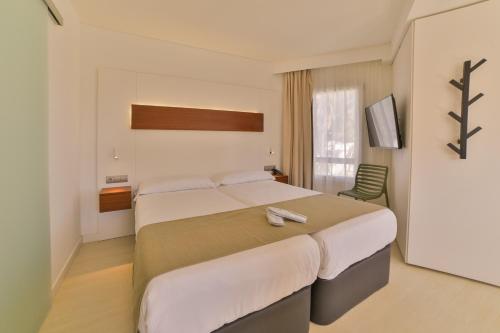 a hotel room with a large bed and a window at Apartamentos Azul Playa in Cala d´Or