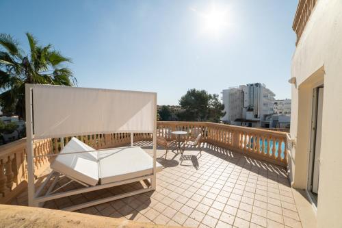 a balcony with a white chair and a table and chairs at Apartamentos Azul Playa in Cala d´Or