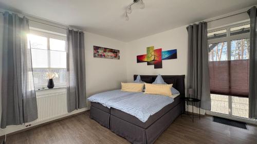 a bedroom with a bed and two windows at Haus am Röblinsee - Ferienwohnungen in Fürstenberg in Fürstenberg-Havel