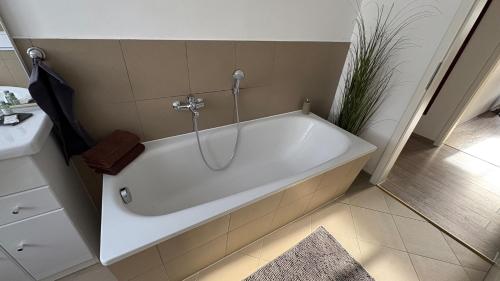a white bath tub in a bathroom with a sink at Haus am Röblinsee - Ferienwohnungen in Fürstenberg in Fürstenberg-Havel