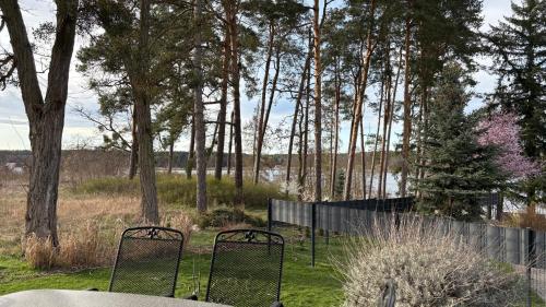 two chairs in a yard with a fence and trees at Haus am Röblinsee - Ferienwohnungen in Fürstenberg in Fürstenberg-Havel