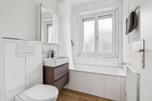 a white bathroom with a sink and a toilet at UP&GREAT Apartments - Stylish City Living in Zürich