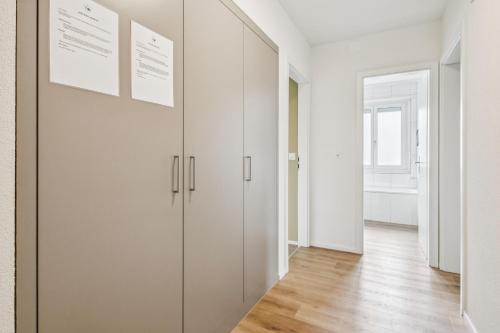 a hallway with white cabinets in a white apartment at UP&GREAT Apartments - Stylish City Living in Zürich