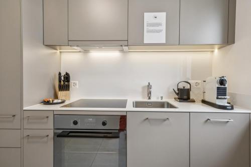 a kitchen with white cabinets and a sink at UP&GREAT Apartments - Stylish City Living in Zürich
