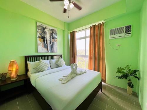 a green bedroom with a bed with a towel on it at Sharon's Island - Newcoast Boracay in Boracay