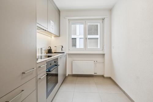 a kitchen with white cabinets and a window at UP&GREAT Apartments - Stylish City Living in Zürich