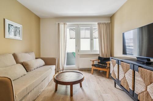 a living room with a couch and a tv at UP&GREAT Apartments - Stylish City Living in Zürich
