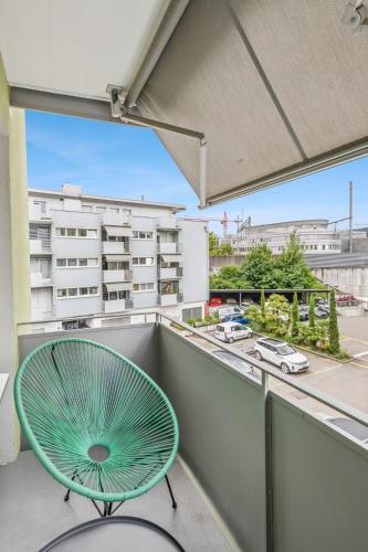 a green chair on a balcony with a view of a building at UP&GREAT Apartments - Stylish City Living in Zürich