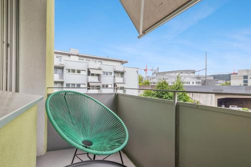 a green chair sitting on the balcony of a building at UP&GREAT Apartments - Stylish City Living in Zürich