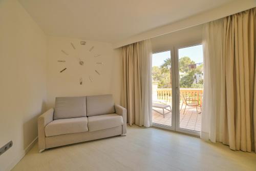 a living room with a chair and a clock on the wall at Apartamentos Azul Playa in Cala d´Or